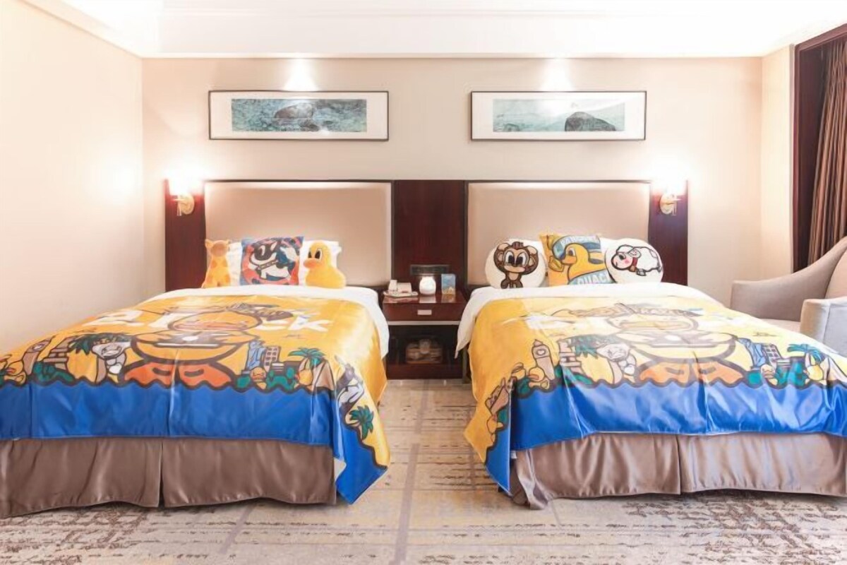 A hotel room with two beds, a nightstand, a desk, and a chair.