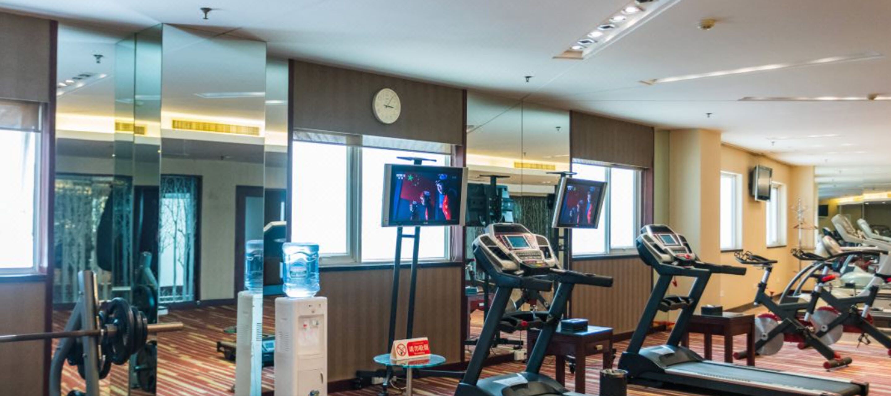 Una palestra alberghiera con tapis roulant, una panca per pesi e distributori d'acqua.