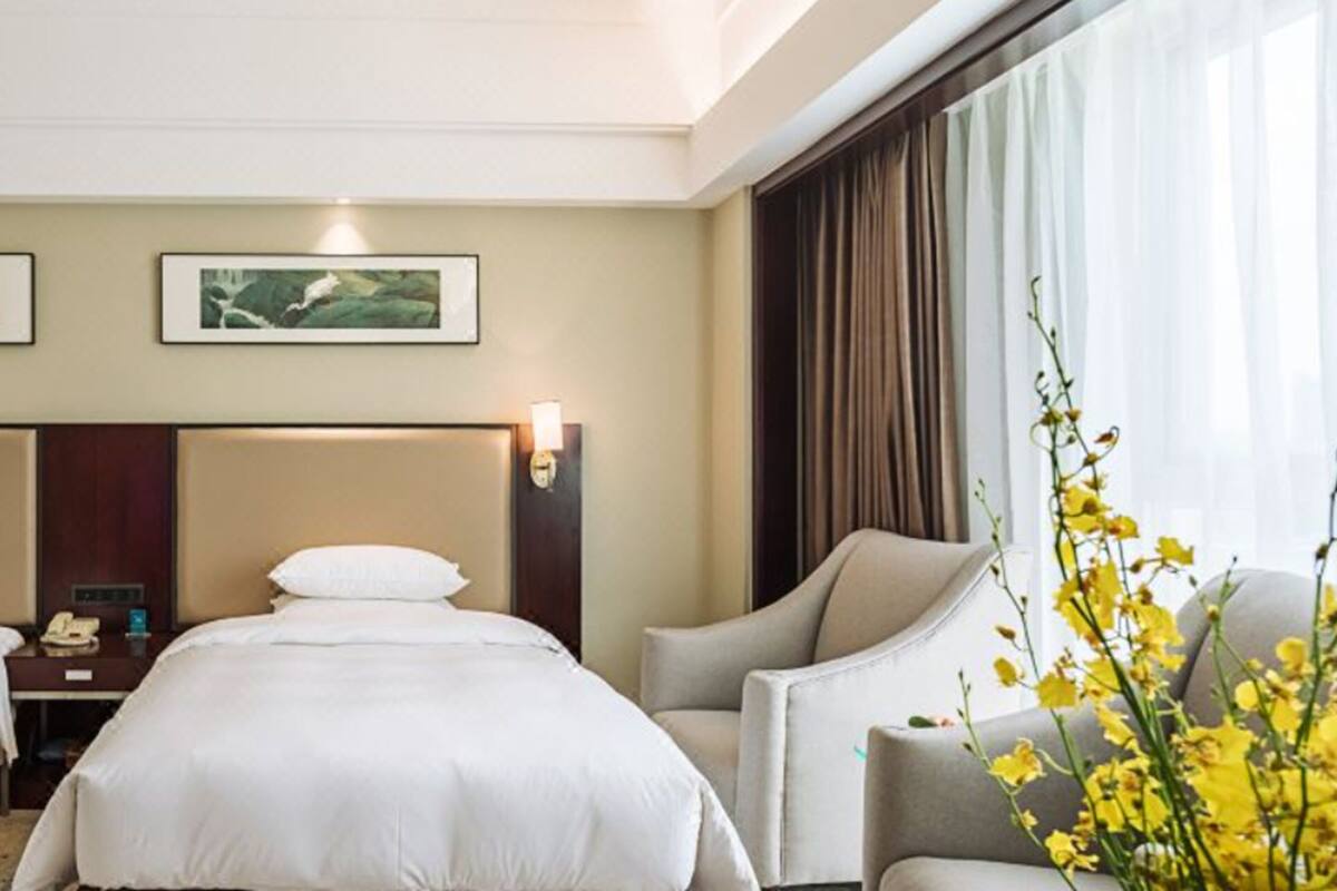 A hotel room with two beds, a desk, and a chair. There are two framed pictures on the wall above the beds.