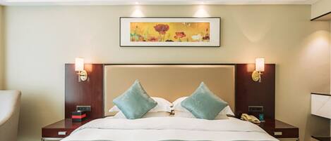 Een hotelkamer met een groot bed, twee nachtkastjes, een schilderij aan de muur en twee wandlampen.