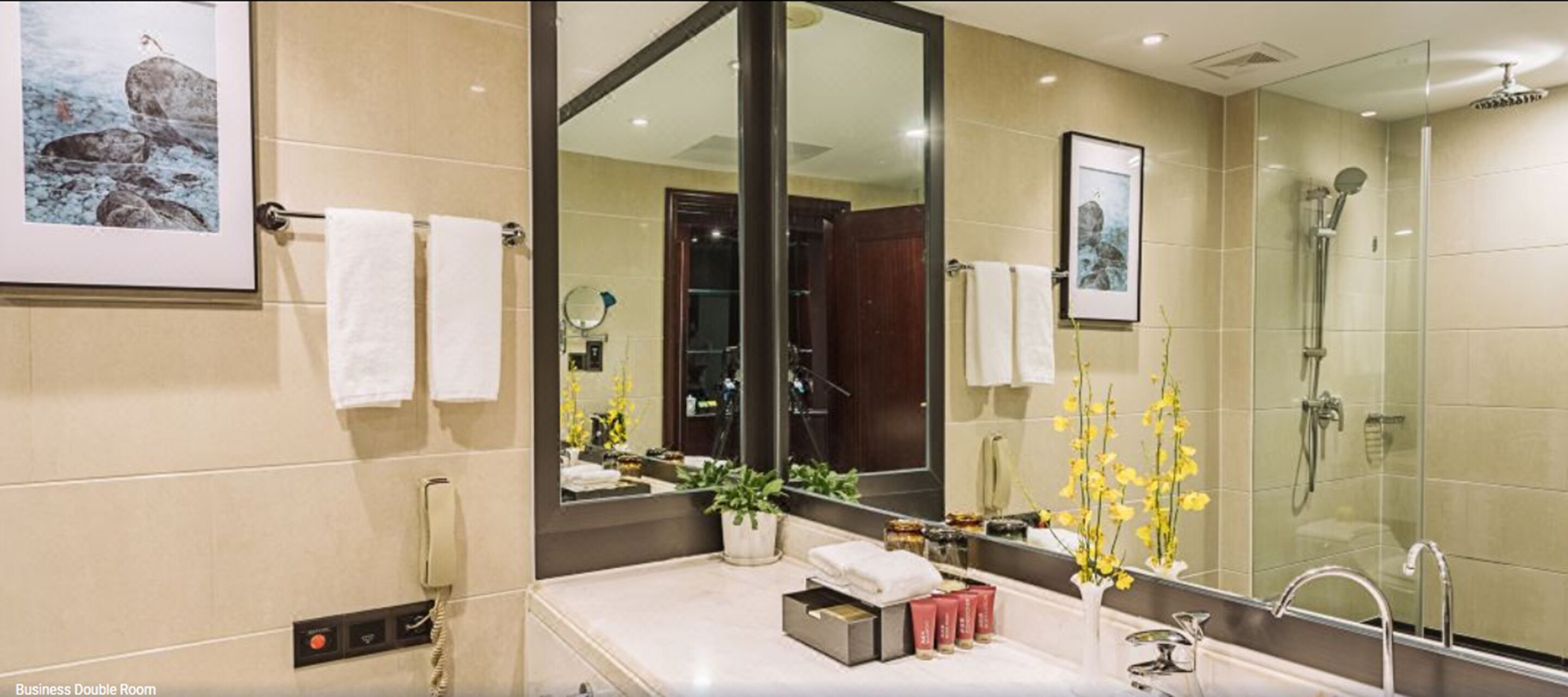 A modern bathroom with a large mirror, a shower, and a sink area with toiletries.