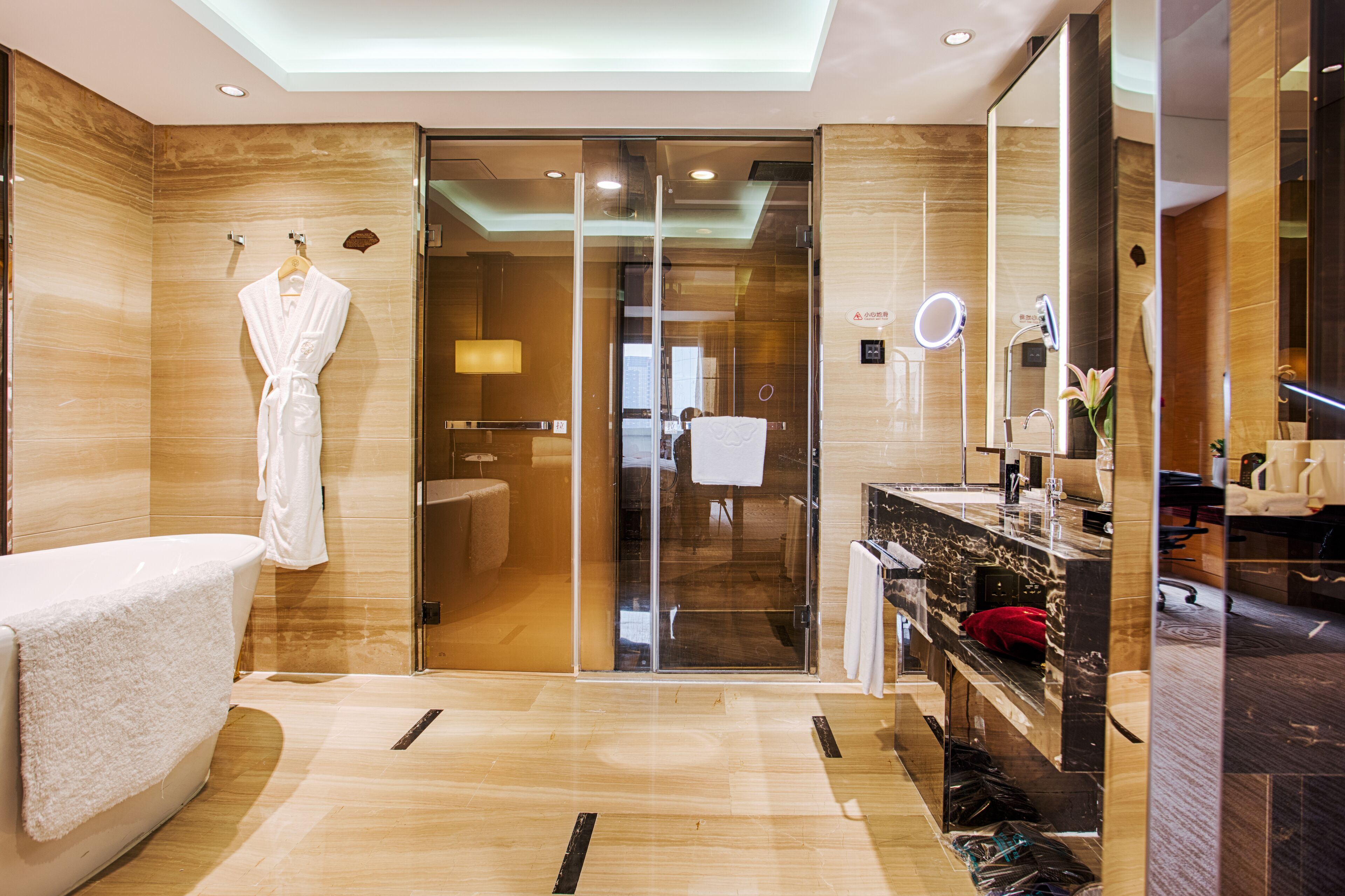 Un bagno moderno con una vasca, un box doccia in vetro, un mobile lavabo con specchio e un accappatoio su un appendiabiti.