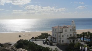 Un edificio costero con una torre destacada, junto a una playa que ofrece vistas claras del mar.