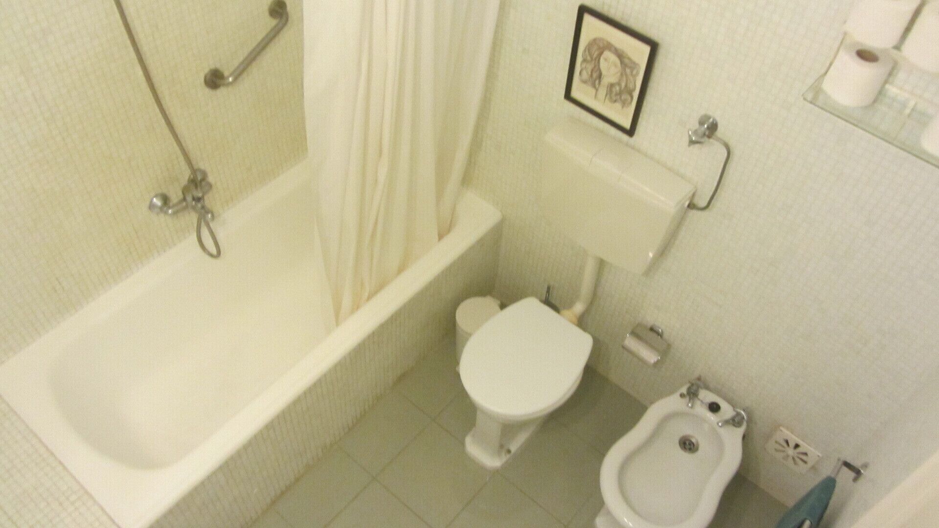 A small bathroom with a bathtub, toilet, and bidet.
