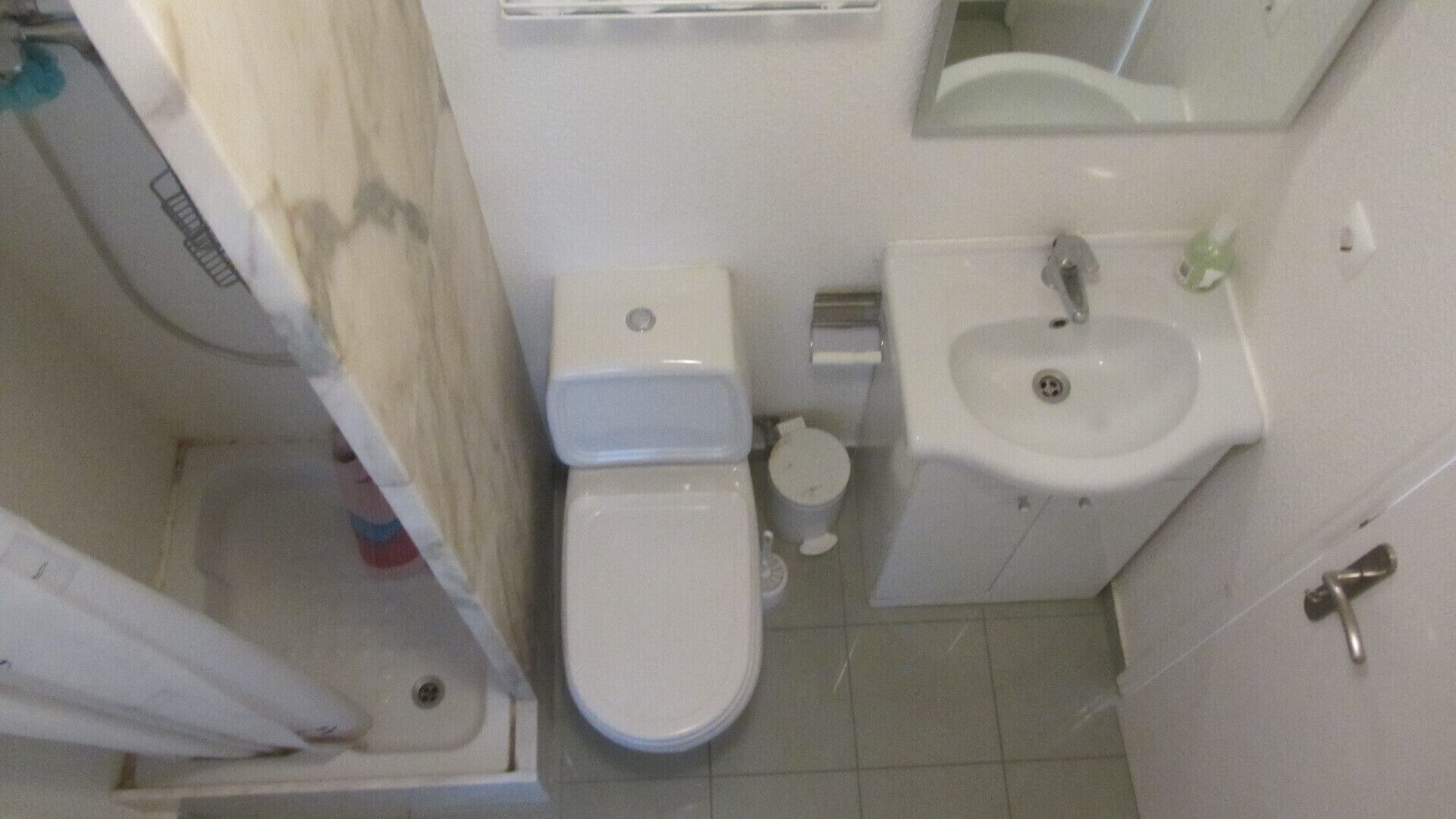 Une petite salle de bain avec des toilettes, un lavabo et un miroir.