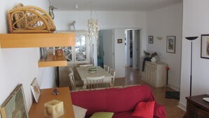 Una sala de estar con un sofá rojo, una mesa de centro de madera y un comedor con mesa y sillas.