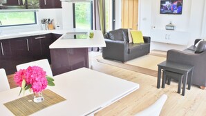 En moderne stue med et hvidt spisebord, sort lædersofa og et lille sort bord.