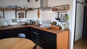 Een kleine keuken met een houten kookeiland, een inbouwoven en hangende keukengerei.