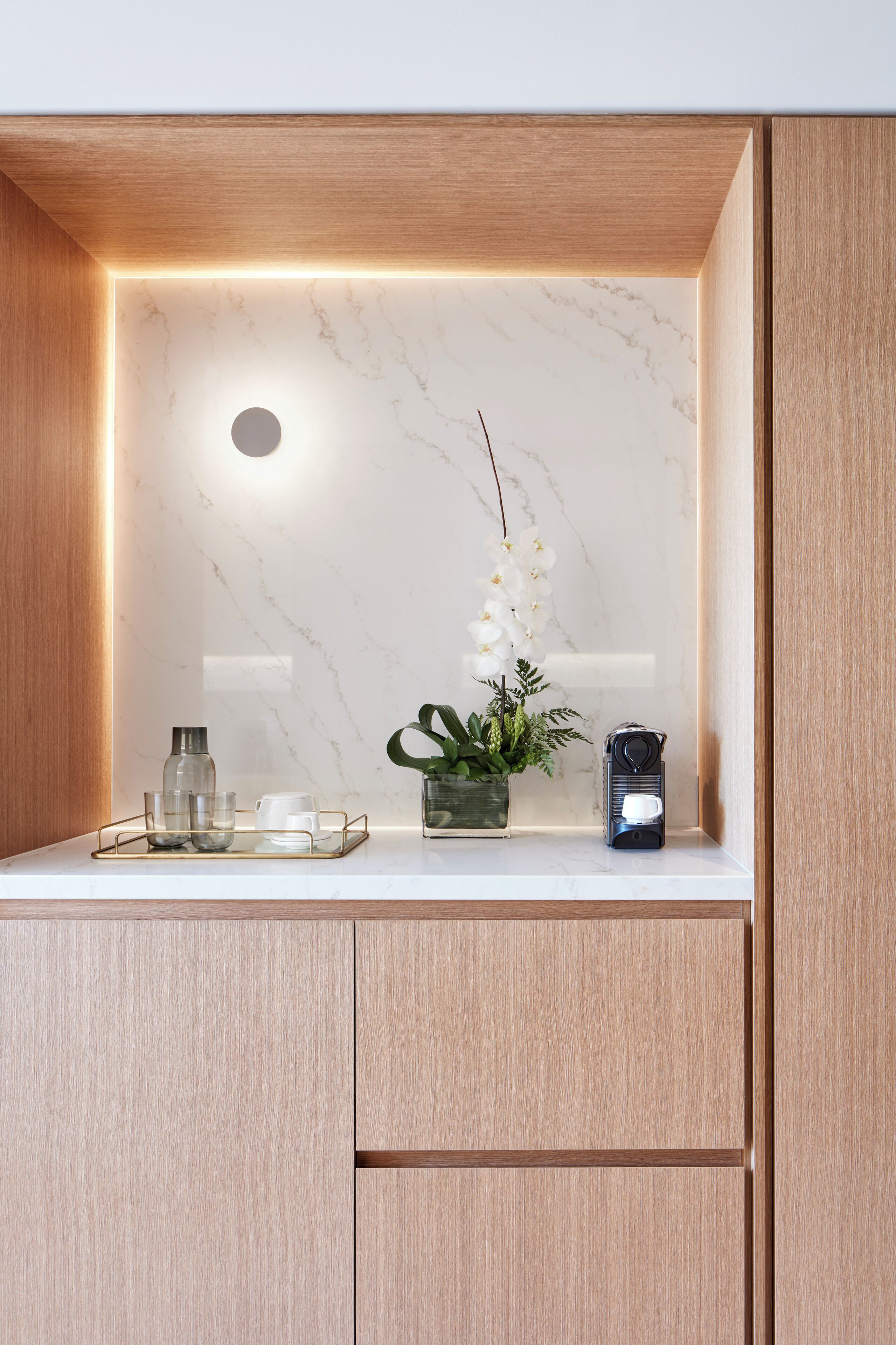 Un meuble-lavabo moderne avec un plan de toilette en marbre, une petite orchidée en pot et une radio.