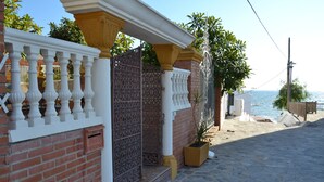 A coastal building with a stone-paved entrance, a white balustrade, and a view of the sea. - Beach house with medieval charm in Chilches Costa (Velez-Malaga)