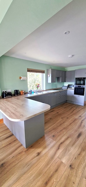 A kitchen with grey cabinets, a wooden countertop, and a built-in oven.