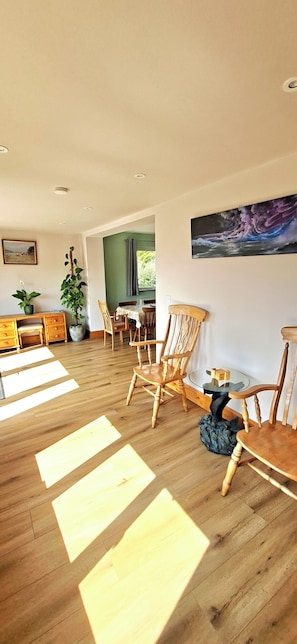 A spacious living area with wooden flooring, a dining table, and several chairs.