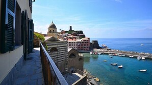 Eine Küstenstadt mit historischen Gebäuden, blauem Meer und einem kleinen Hafen mit Booten.