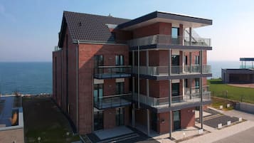 Un immeuble moderne à plusieurs étages, doté d’une façade en briques, de balcons et offrant une vue sur la mer.