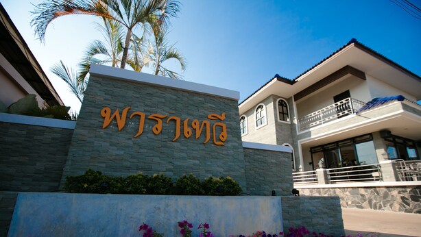 Un bâtiment à la façade en pierre, sur lequel on peut voir une enseigne avec des caractères thaïlandais.