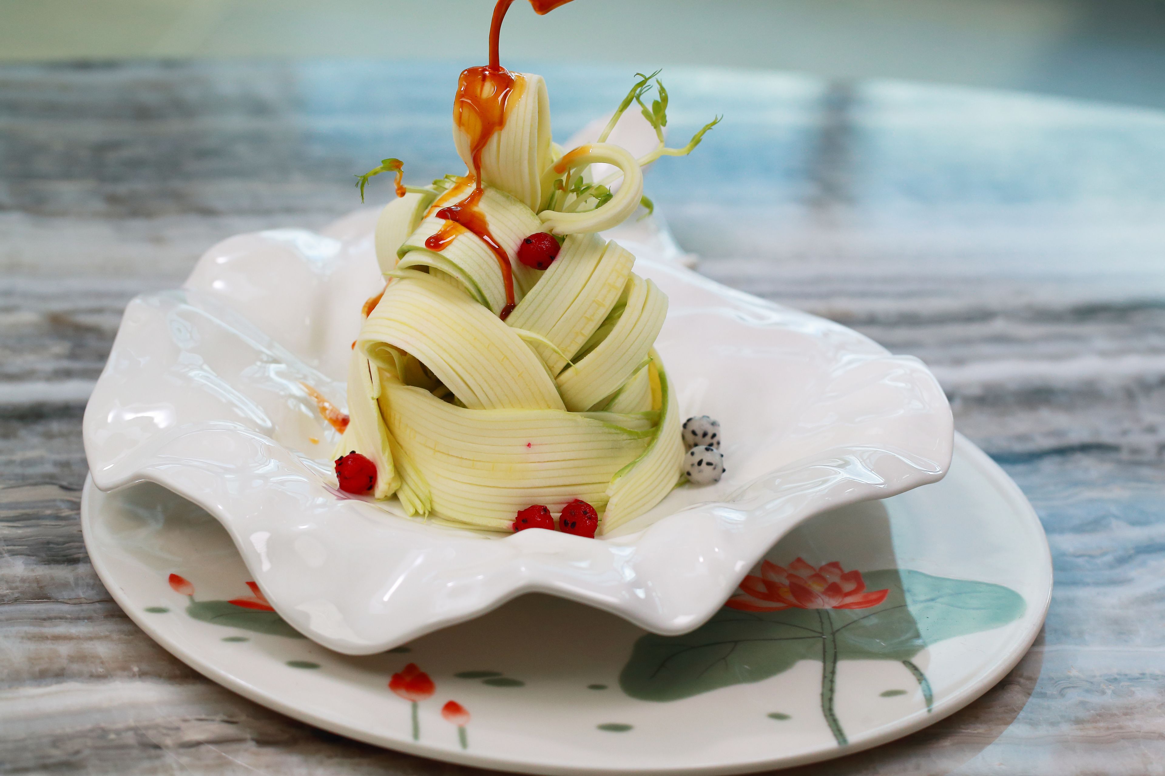 A decorative plate with a floral design and a central arrangement of food.