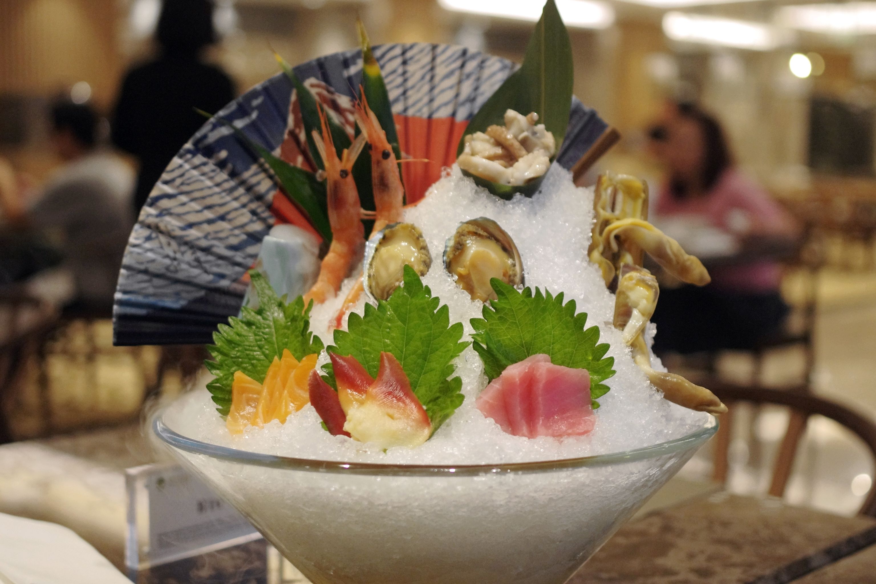 A bowl of ice with seafood and garnishes.
