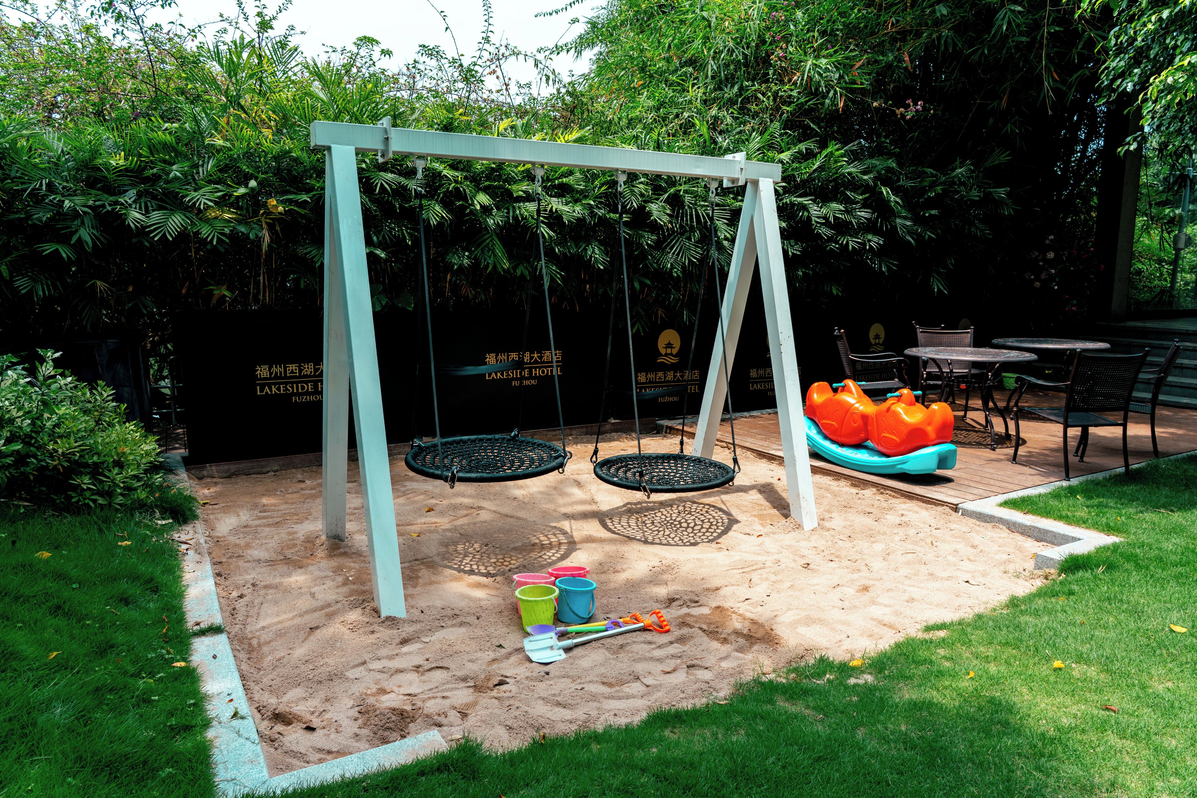 A garden with a swing set, a small table, and a bench.