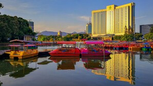 Un hotel frente al agua con varias embarcaciones de colores amarradas, reflejando el hotel y los edificios circundantes.