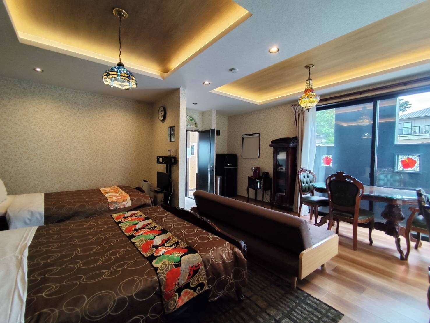 Habitación de hotel con una cama grande, un sofá, una mesa de comedor con sillas y vistas al exterior.