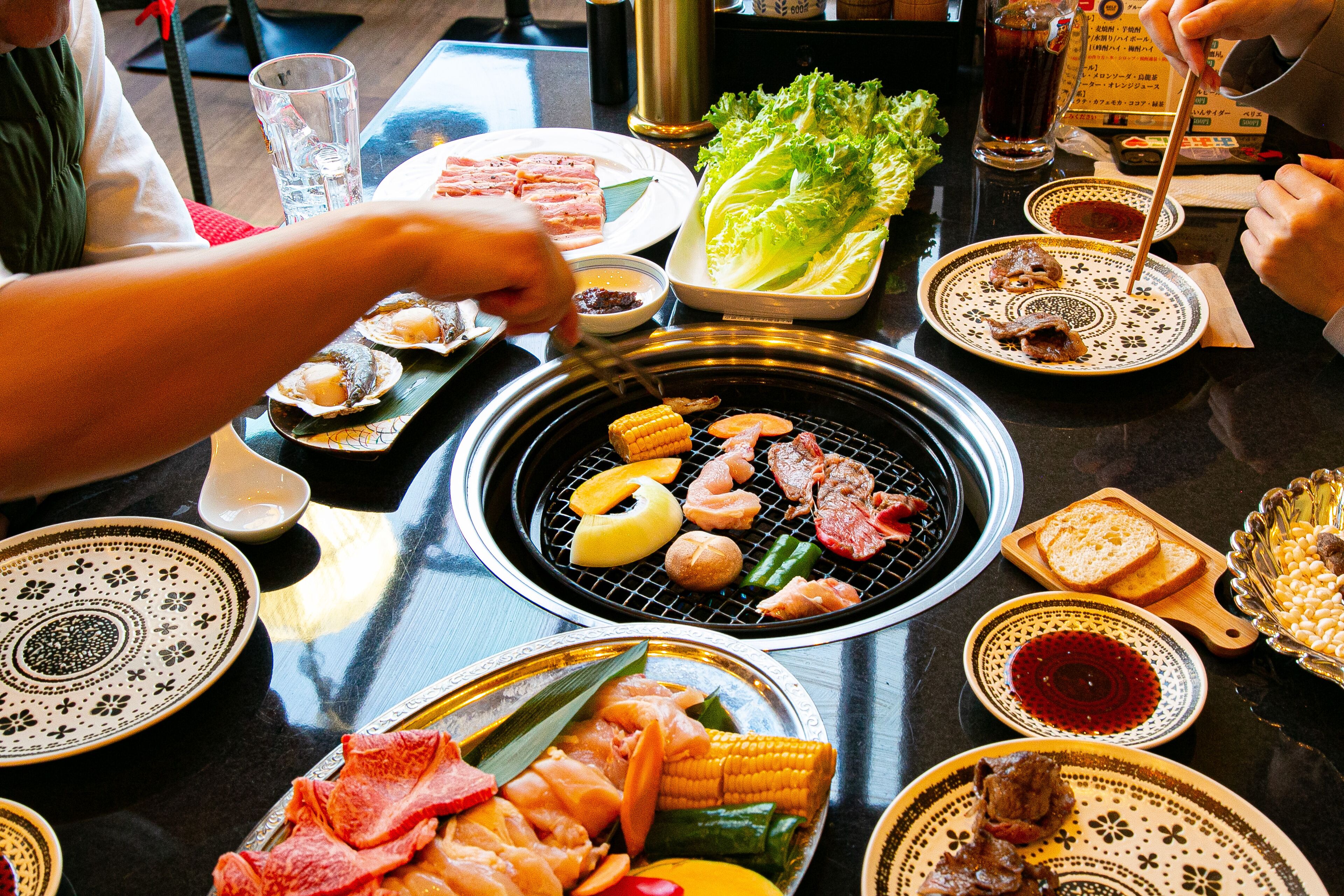 A dining table with various dishes, including seafood and vegetables, and a grill in the center.