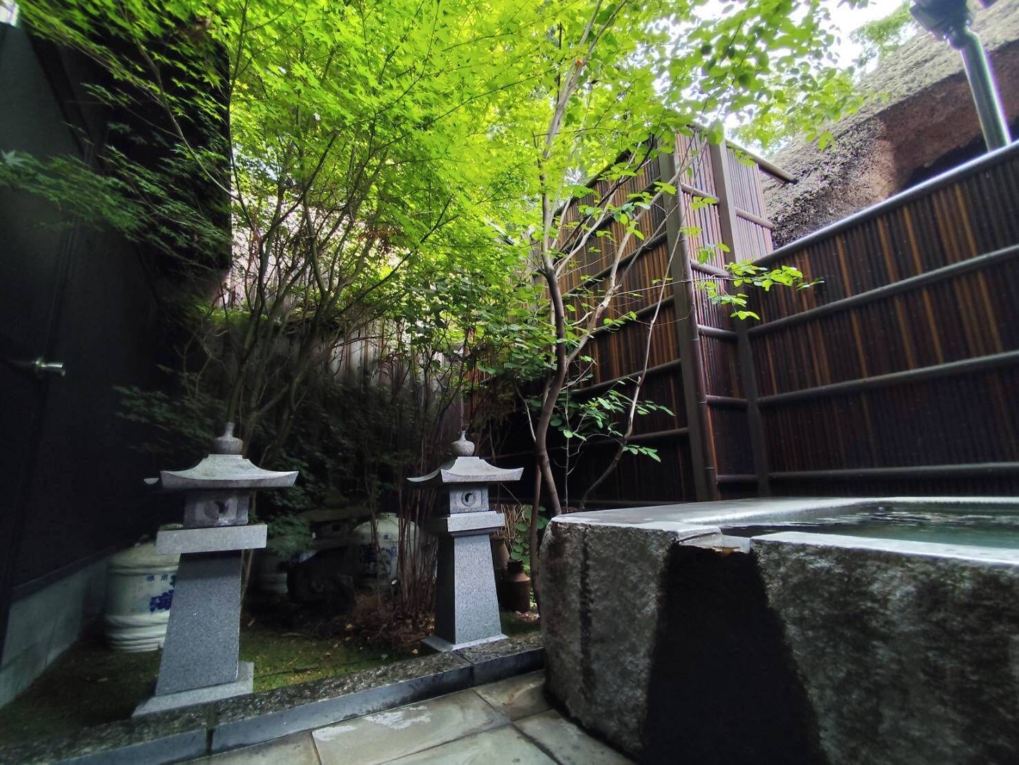 A traditional Japanese garden with stone lanterns, a koi pond, and bamboo structures.