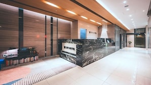 Ein moderner Hotel-Empfangsbereich mit einer Marmor-Rezeption, Holzpaneelen und einem hellen, freundlichen Ambiente.