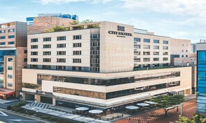 A modern hotel with a flat roof, multiple floors, and a ground-level restaurant with outdoor seating. - Wonju City Hotel HYEOKSIN (Wonju)