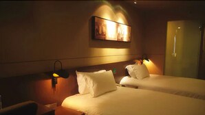 A hotel room with two beds, a nightstand, a lamp, and a painting on the wall. - Jin Jiang Inn ShangHai HongQiao Station (Shanghai)
