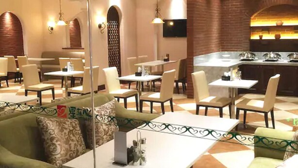 A restaurant with a modern interior, featuring a mix of dining tables and booths, a brick accent wall, and contemporary lighting fixtures. - Jin Jiang Inn ShangHai HongQiao Station (Shanghai)