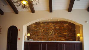 A reception area with a stone wall, wooden reception desk, and a chandelier. - Jin Jiang Inn ShangHai HongQiao Station (Shanghai)