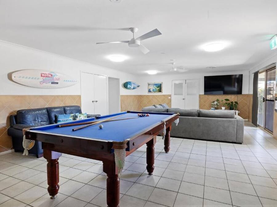 Ein Billardtisch in einem Raum mit einer Couch und einem Fernseher.