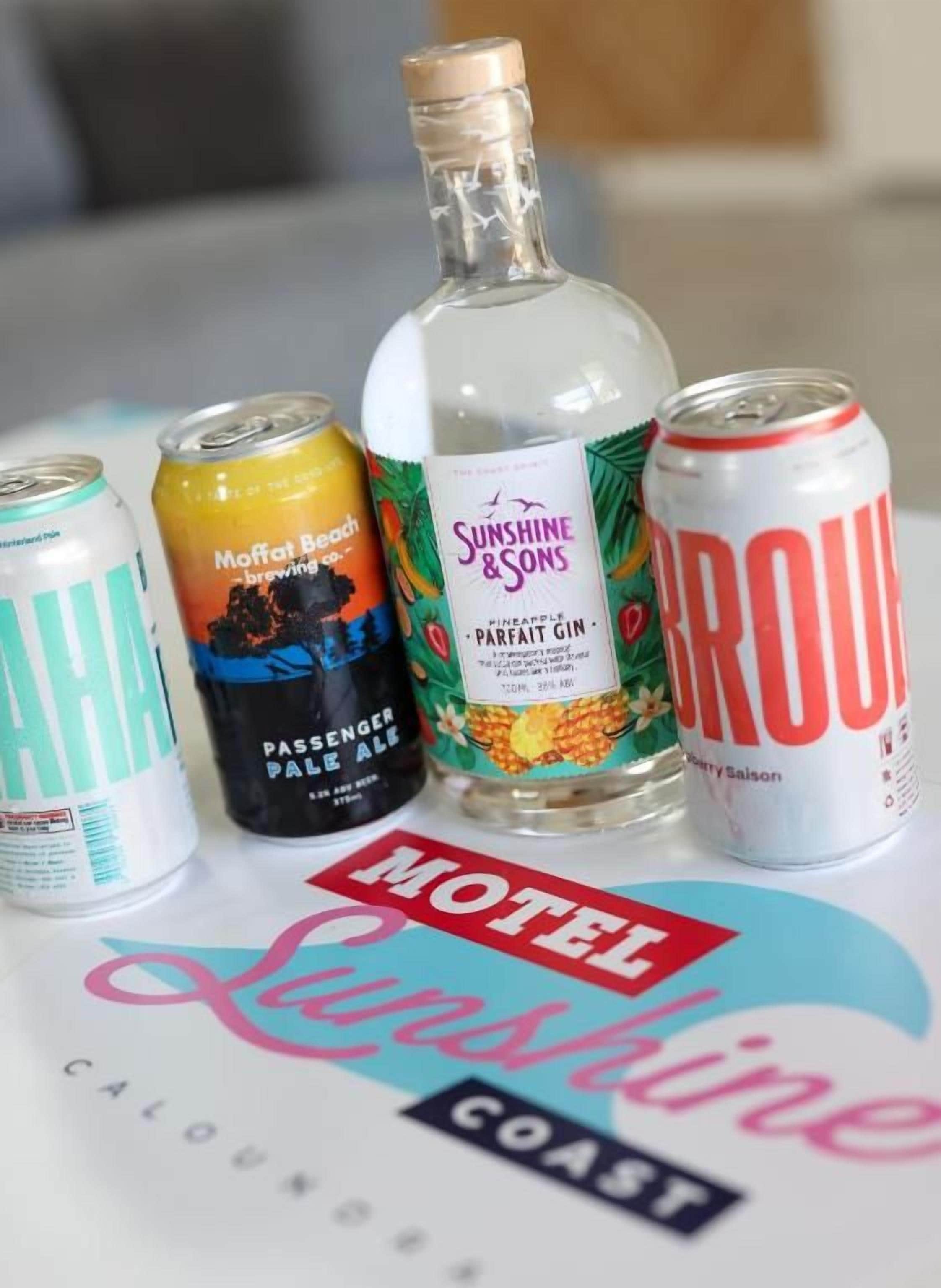 A collection of beverages including a bottle of Sunshine & Sons, a can of Moffat Beach, a can of Grouv, and a can of Passengermale Pale Ale.