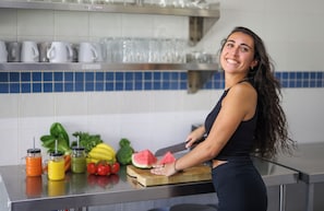 Una encimera de cocina con tabla de cortar, un cuchillo y diversas frutas y verduras.