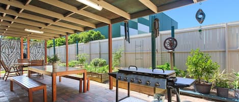 An outdoor patio with a grill, seating area, and potted plants.