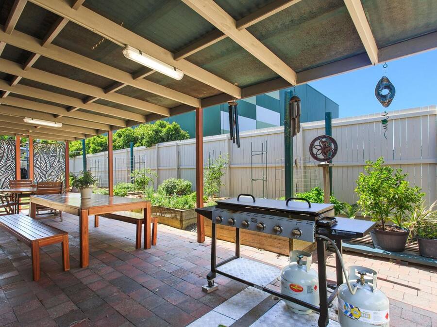 An outdoor patio with a grill, seating area, and potted plants.