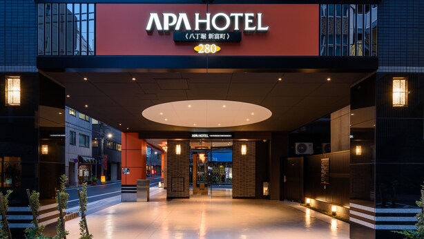 Exterior do APA HOTEL com design moderno, destacando uma entrada imponente e uma visão clara da área de recepção.