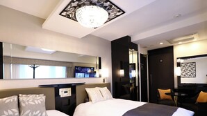 Quarto de hotel com duas camas, uma escrivaninha, uma cadeira, um espelho e um lustre.