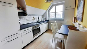 Una cocina moderna con armarios blancos, encimera negra y una ventana sobre el fregadero.