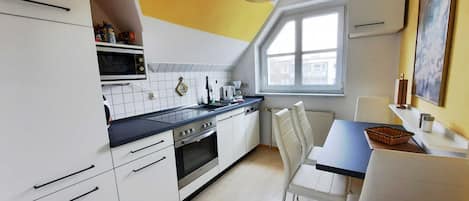 Une cuisine moderne avec des meubles blancs, un plan de travail noir et une fenêtre au-dessus de l’évier.