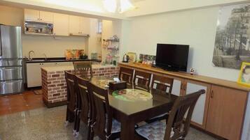 A compact kitchen with a dining area, a refrigerator, a sink, and a television.