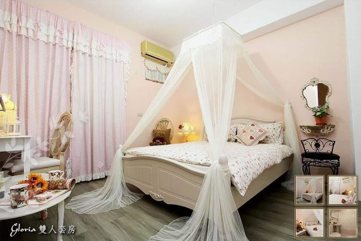 A bedroom with a canopy bed, a bedside table with a lamp, a chair, and a small table with decorative items.