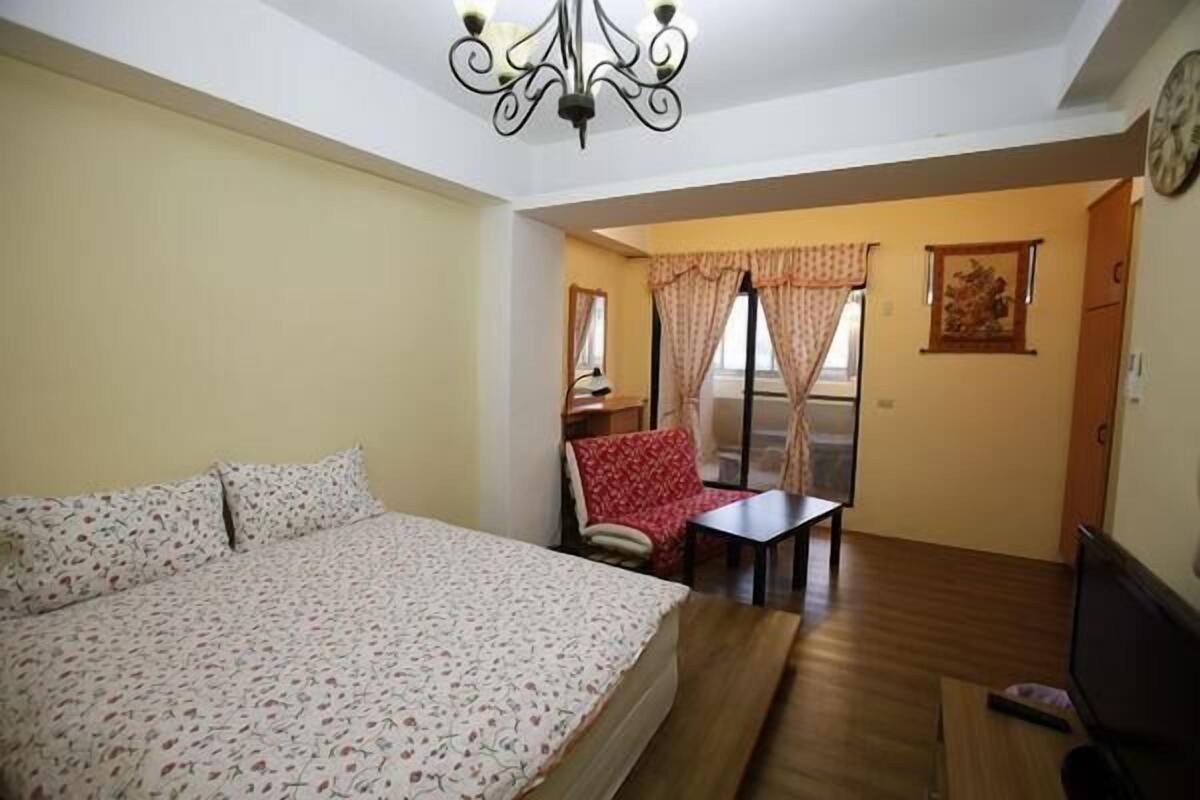 A bedroom with a bed, a desk, and a chair.
