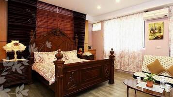A bedroom with a wooden bed, a bedside table, a nightstand, a sofa, and a coffee table.
