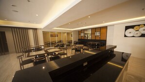 A modern restaurant with a long counter, multiple tables, and chairs. - NS Royal Hotel (Cebu City)