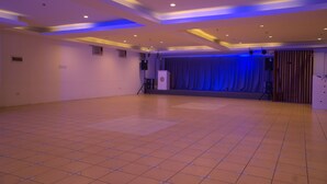 A spacious hall with a tiled floor, a stage with curtains, and a podium. - NS Royal Hotel (Cebu City)