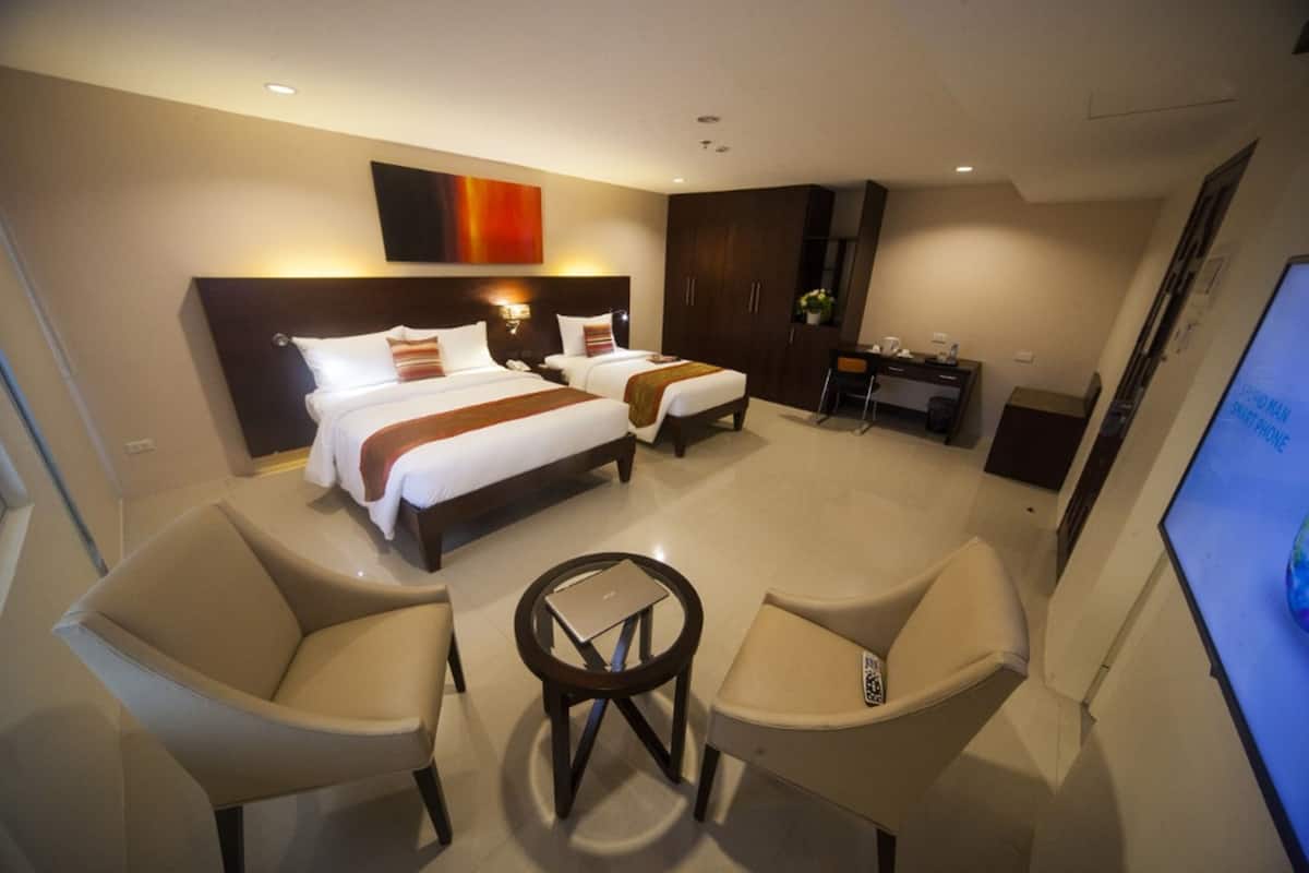 A hotel room with two beds, a desk, a chair, and a small table.