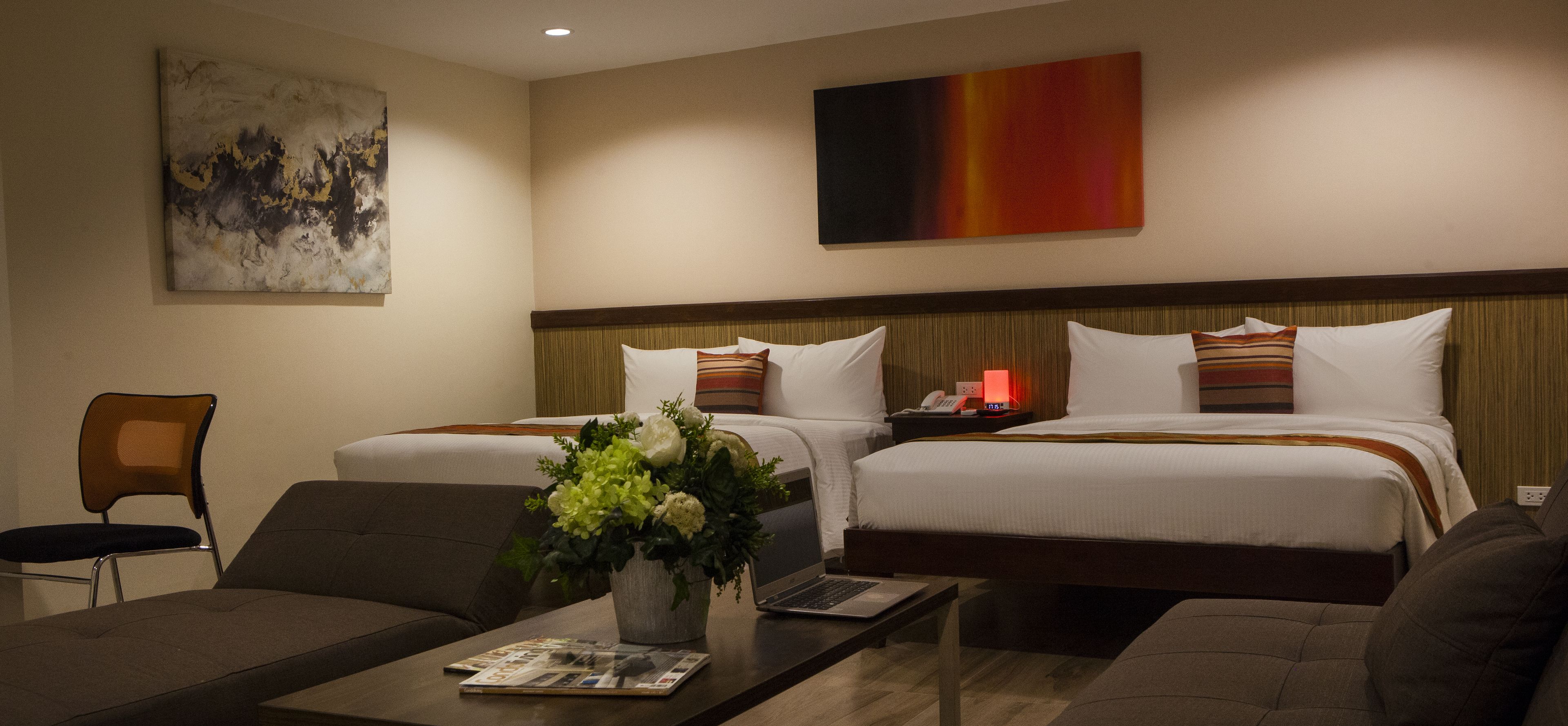 A hotel room with two beds, a desk, a chair, and a coffee table.