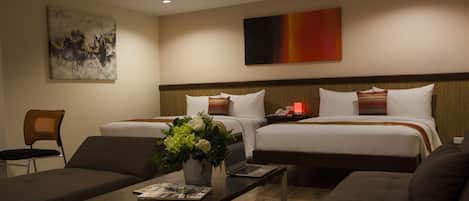 A hotel room with two beds, a desk, a chair, and a coffee table.