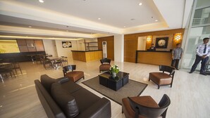 A spacious lobby with a reception desk, seating area, and a kitchen in the background. - NS Royal Hotel (Cebu City)
